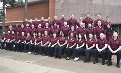 Image: Class #55 grouped in front of red brick building.